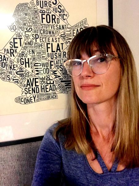 Woman in front of a framed picture of a stylized map of Brooklyn